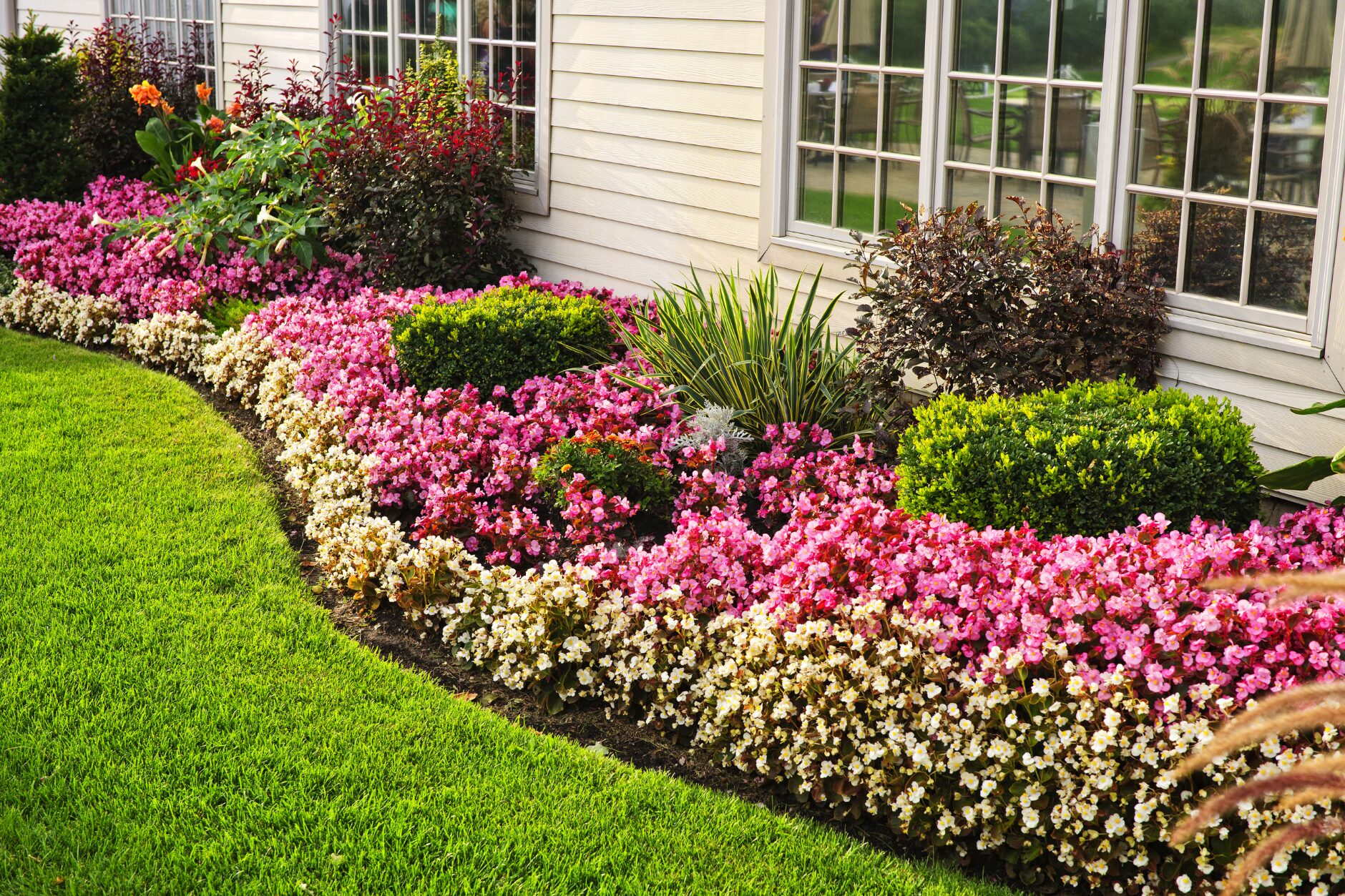 A vibrant green lawn with a colorful flower bed in full bloom, representing spring lawn rejuvenation. Lawn Care Bucks County