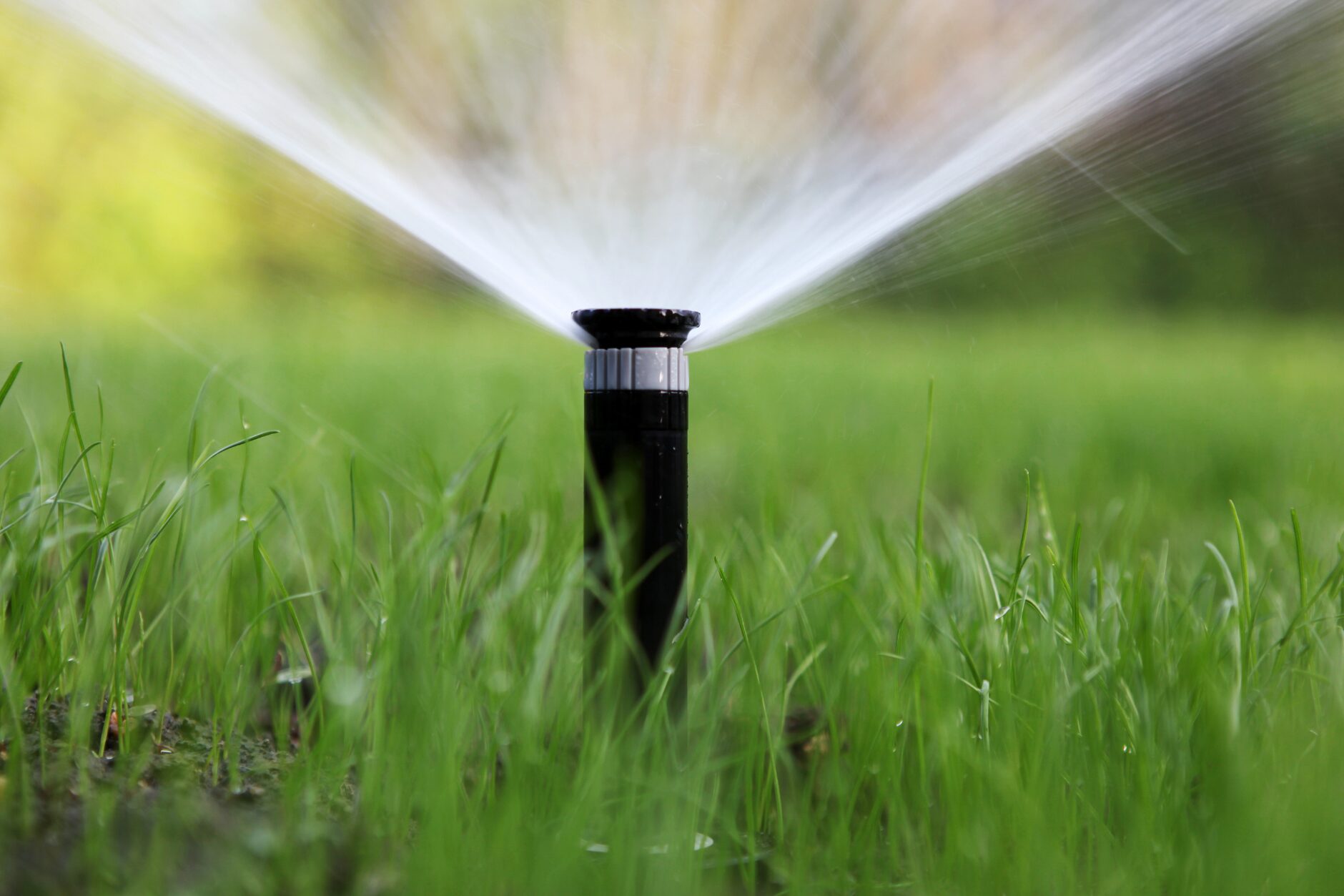 A water sprinkler system in action, keeping the green grass hydrated on a bright summer day. Lawn Care Bucks County